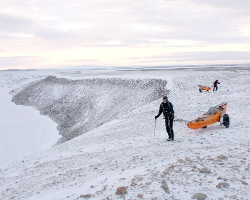 Both hauling along top of snow covered esker