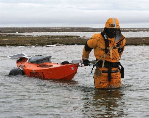 Wading across shallow river in drysuit hauling PAC behind us, wheels down.