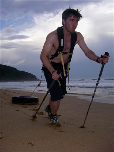 Chris hauling truck tyre along beach